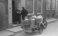 221106 Afbeelding van een melkventer in dienst van melkboer A. van Schaik, met zijn melkkar voor het huis Boothstraat ...